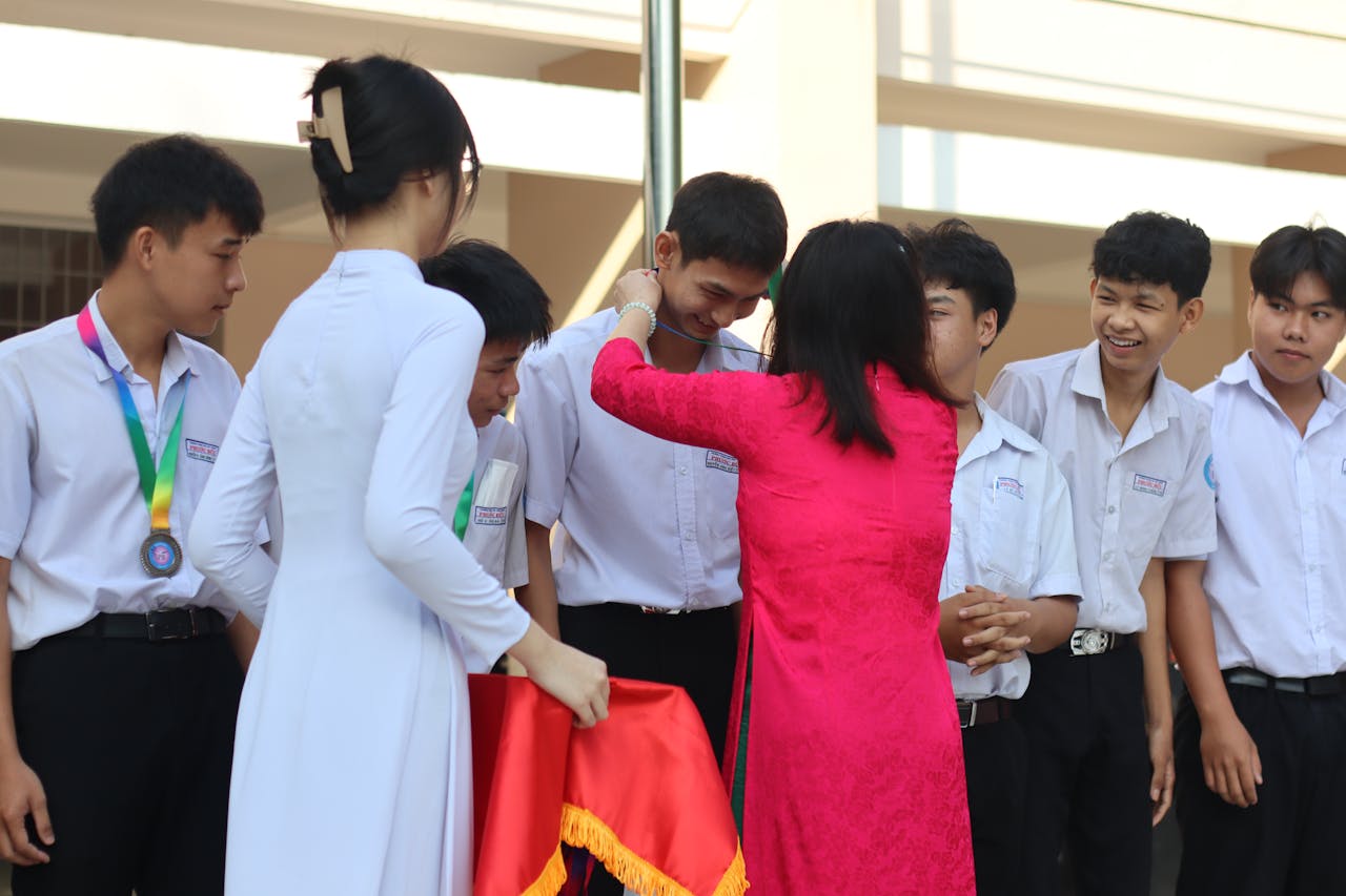 Group of students receiving medals during a school ceremony outdoors.